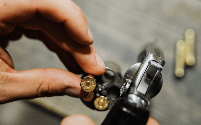 A man is loading bullets into a gun at the range.